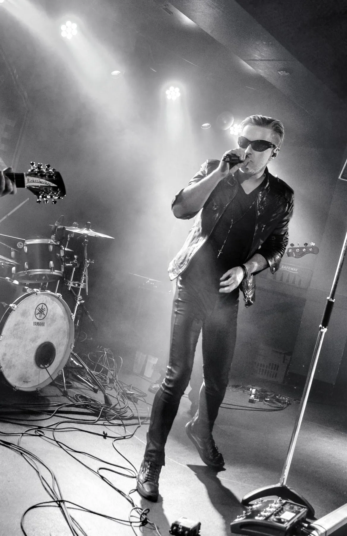 U2.V2 frontman singing into a handheld mic under stage lights
